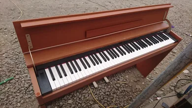 操作ボタンと鍵盤、木目調の本体が見える電子ピアノ